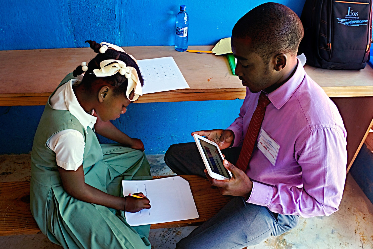 Un enqueteur muni d'une tablette évalue les compétences de lecture d'une fillette